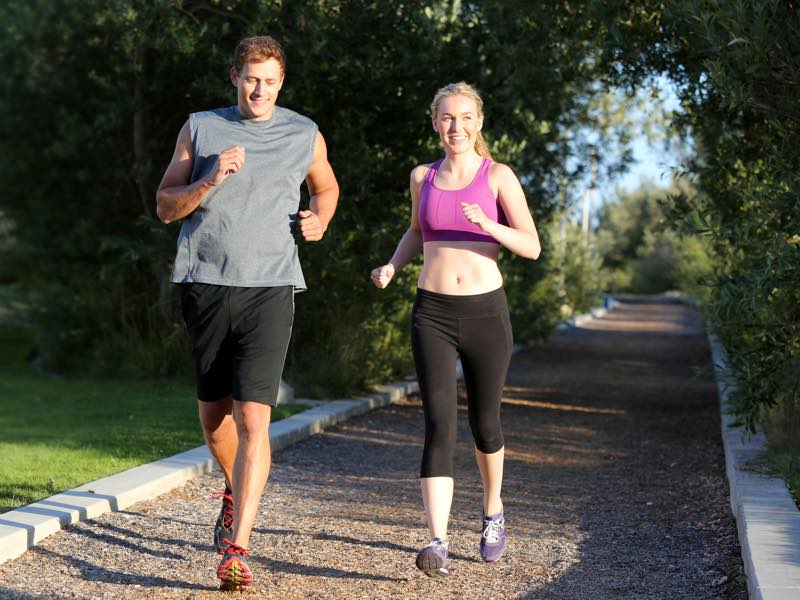 Happy couple running outside in a park injury free