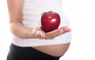 A picture of a pregnant lady holding an apple.