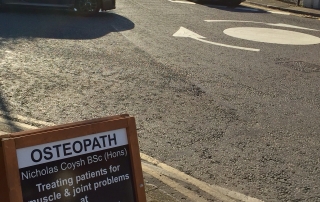 A picture of my A-Board in the street, opposite the shop, pointing patients over the road.